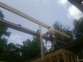 Carpenter setting a ridge beam over a new addition frame — Ice Dam Removal by Roofing Brothers in Grand Ridge