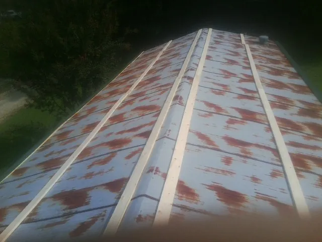 Rusted metal roof panels with new wood purlins before replacement — Storm Damage Roof Repair in Grand Ridge by Roofing Brothers