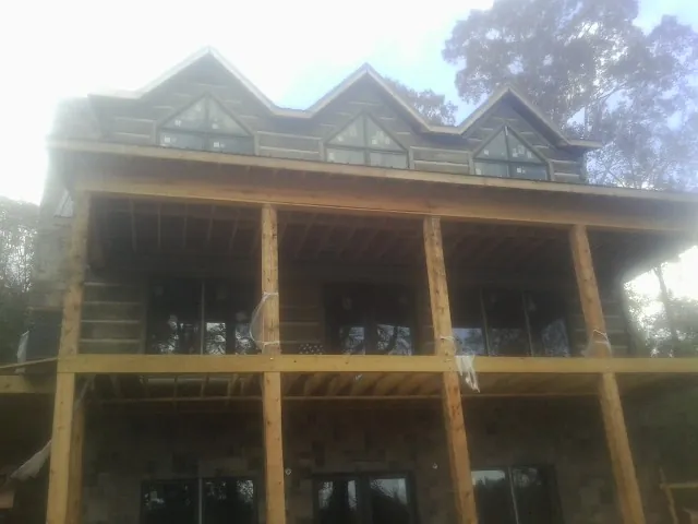 Dormers and porch framing on a large log home under construction — Roof Coating work by our crew in Grand Ridge
